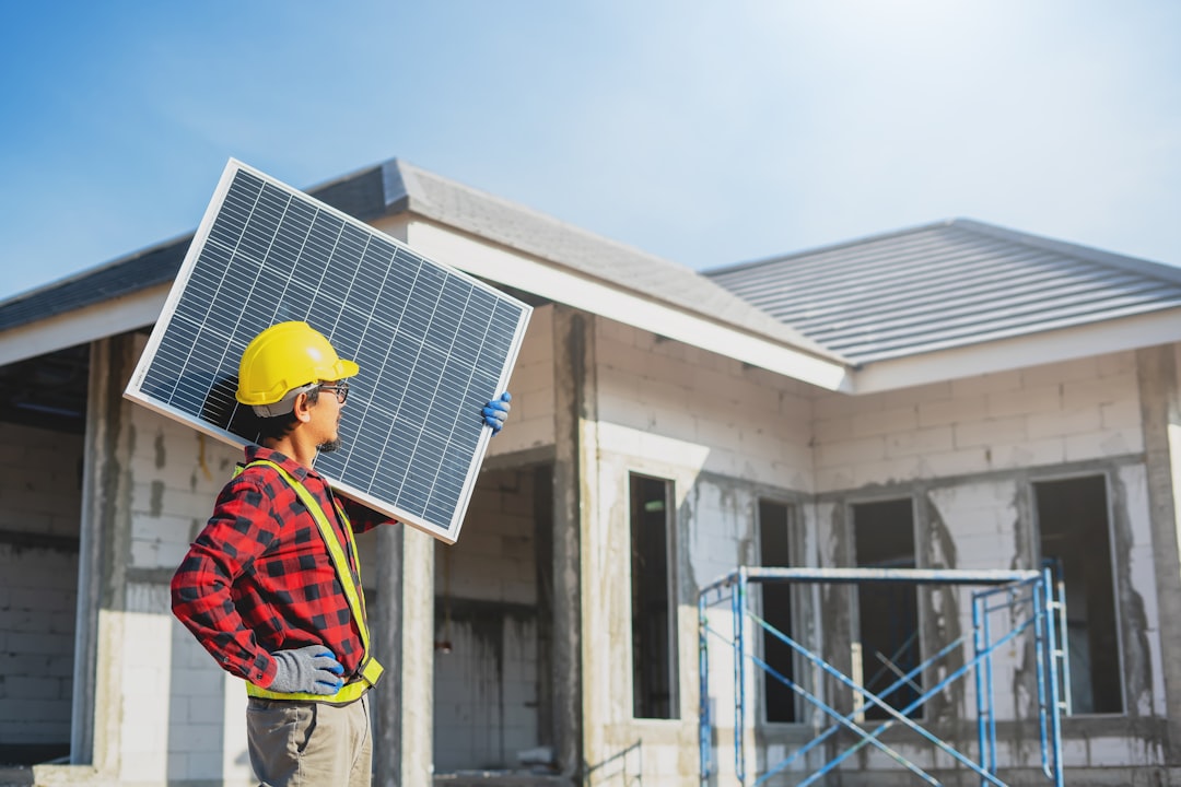 Services Asian construction worker holding metal sheet installation tool to build industrial factory roof.